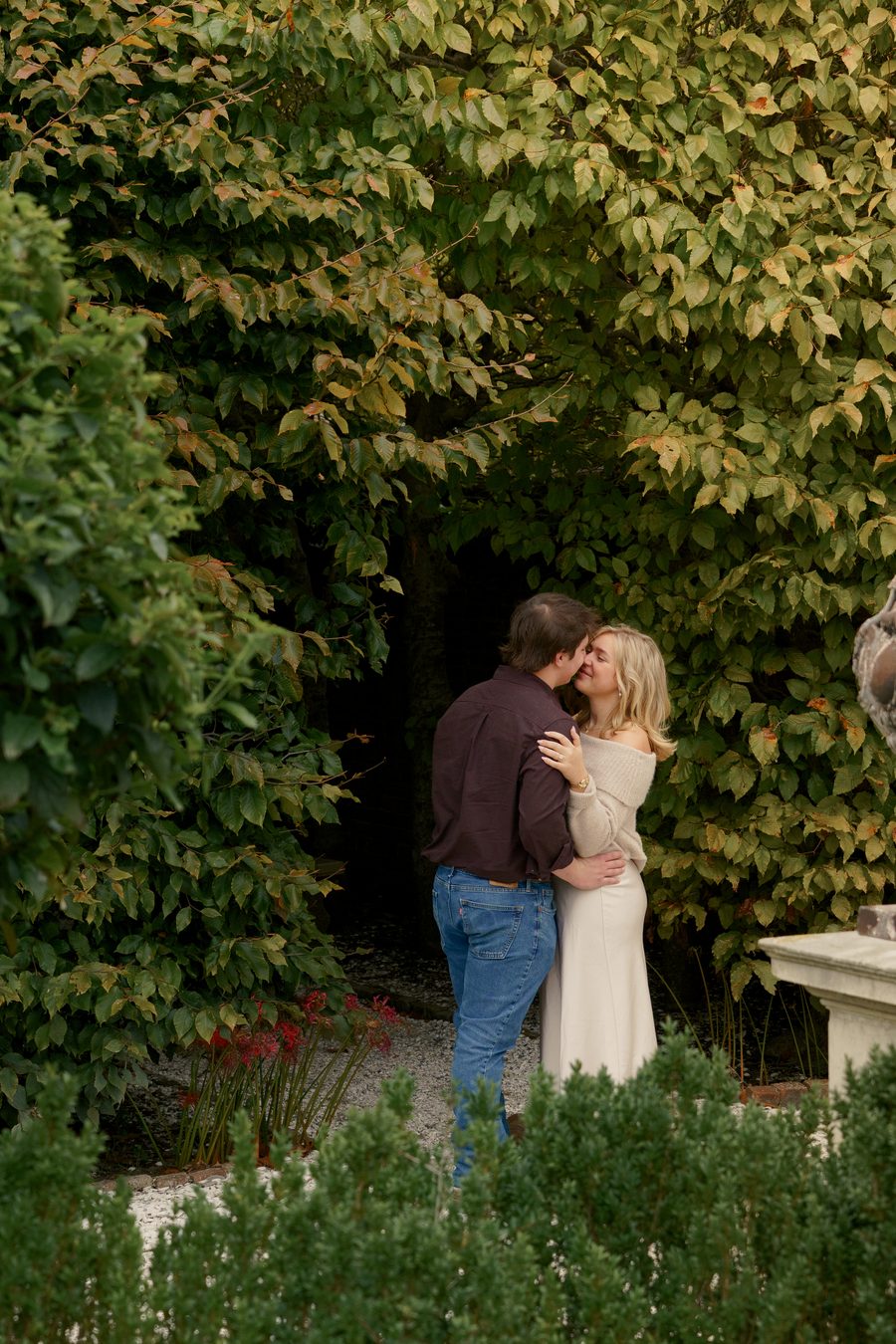 A couple embracing beside an ivy wall in a formal garden