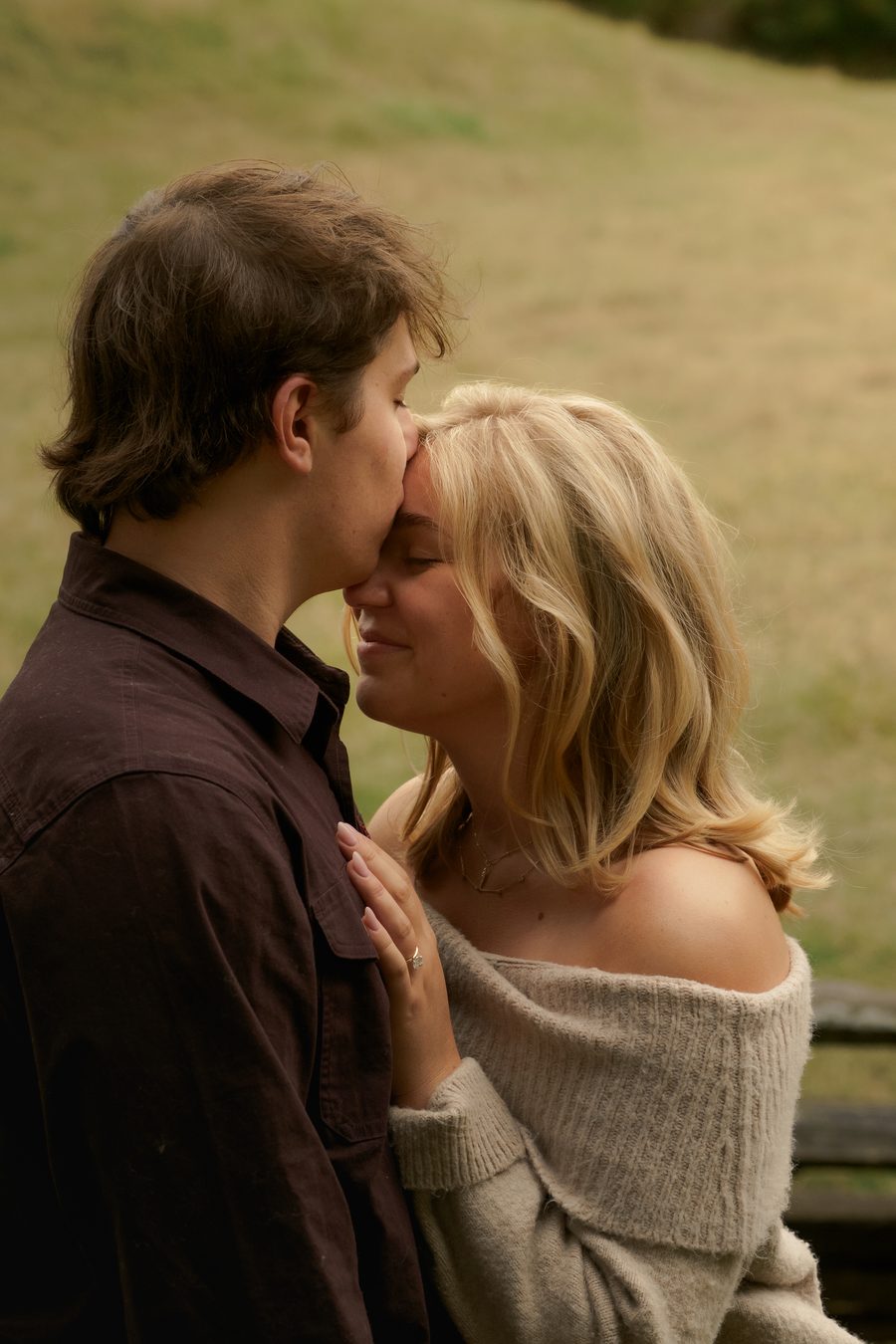 His forehead resting against hers on a grassy hillside