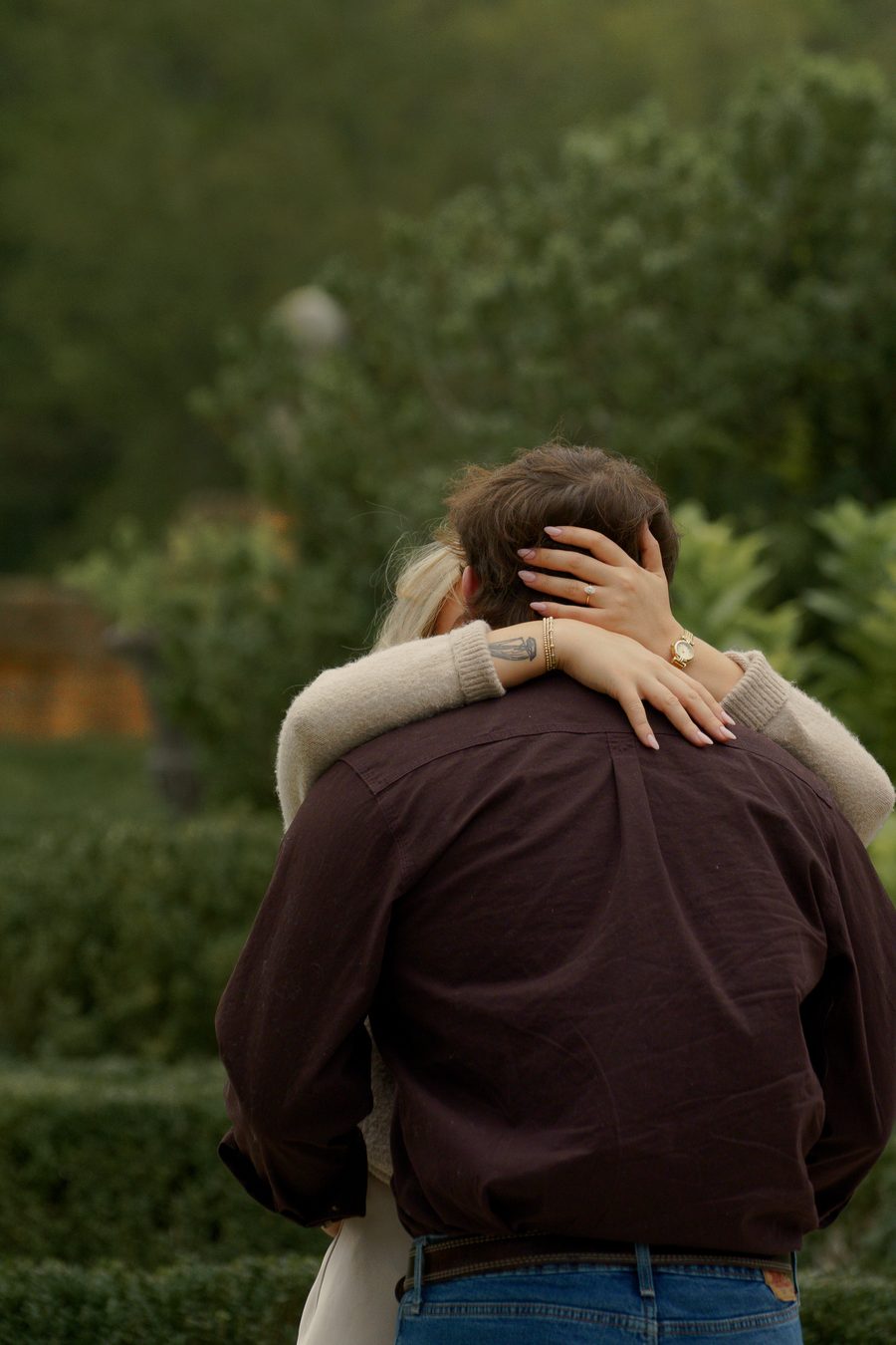 Her arms around his neck among garden hedges