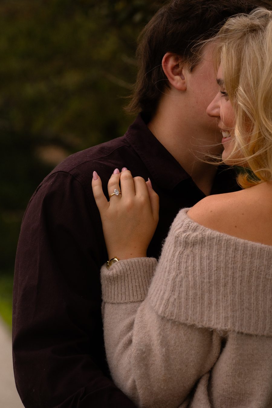 A close frame of her hand on his shoulder as she smiles