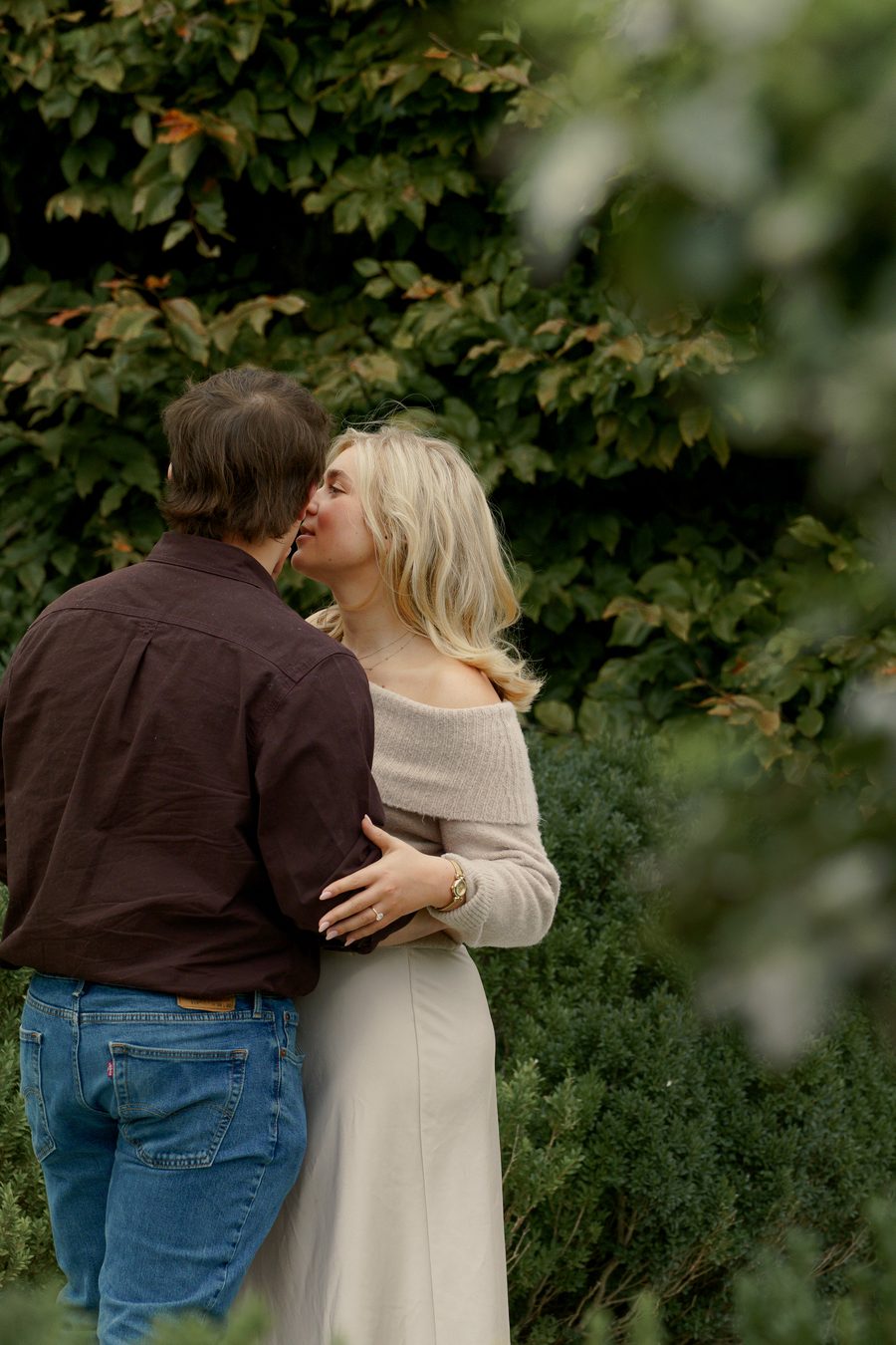 A kiss framed by soft green leaves
