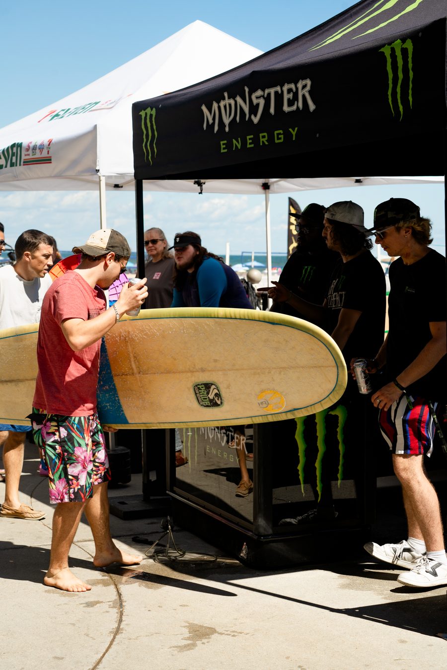 A surfboard carried past the tents between heats