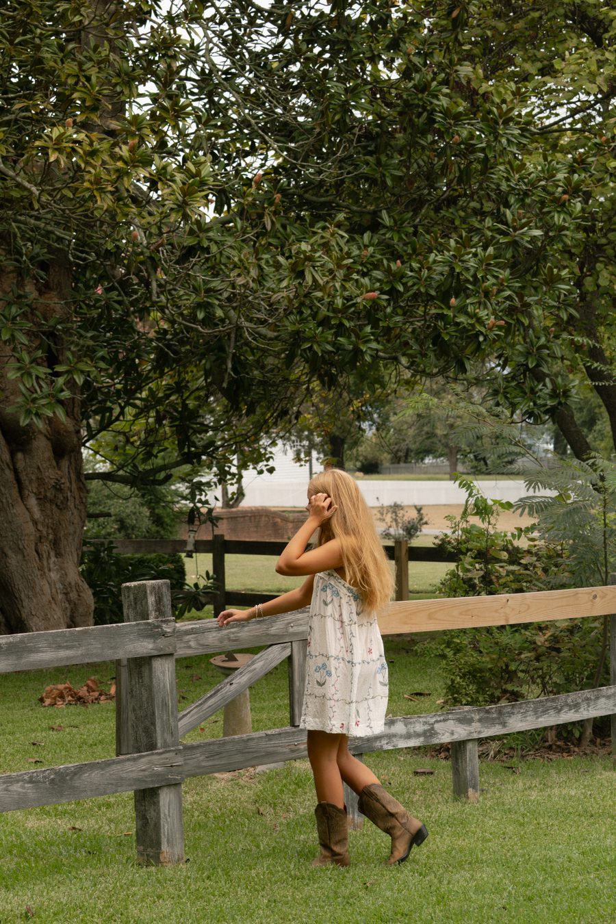 A portrait subject resting against a split rail fence