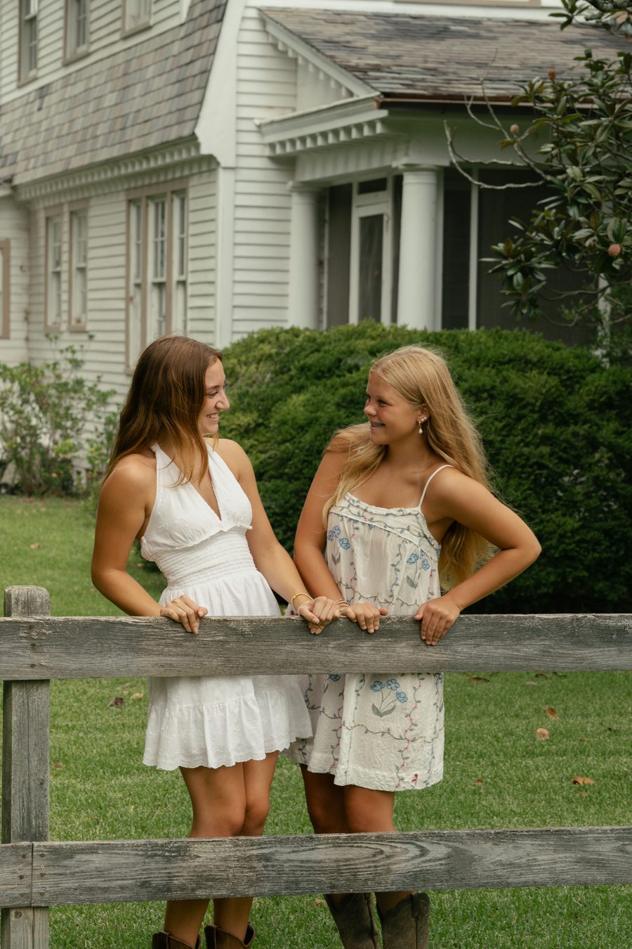 Two friends laughing together at a fence line