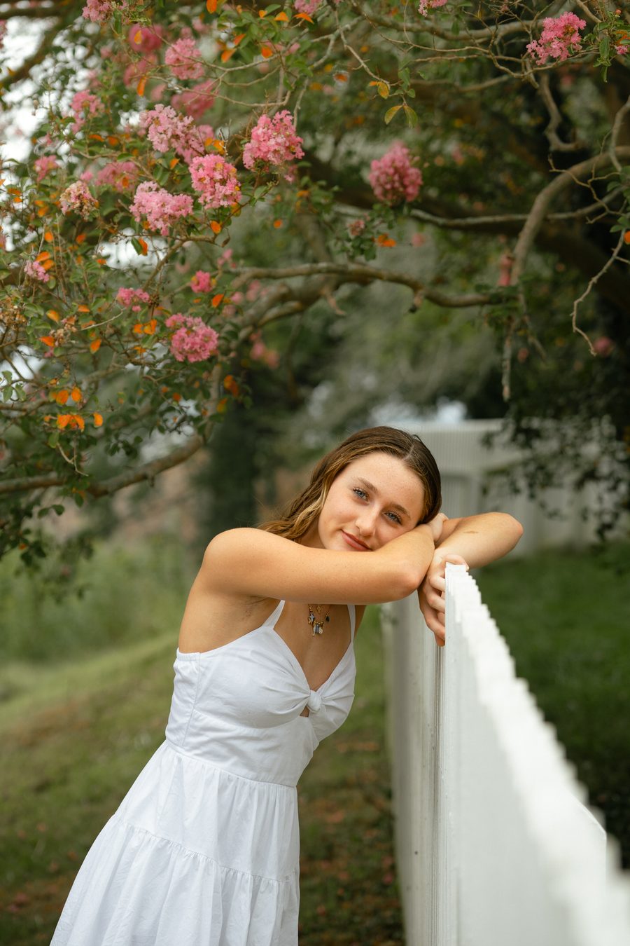A portrait subject resting on a white picket fence